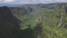 Drone flies across valley partially covered by clouds