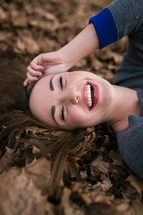 happy young woman lying in fall leaves 