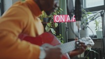 Black Musician Singing and Playing Guitar as Broadcasting Radio Show
