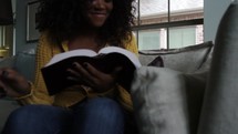 Woman sitting on the couch, reading the Bible.
