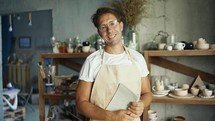 Portrait of a young happy potter posing in his pottery studio.