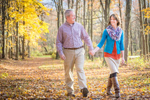 couple walking holding hands in a fall forest 