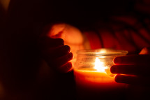 Hands holding candle in dark