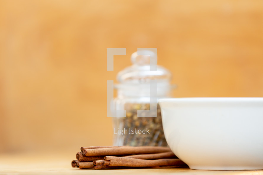 Organic cinnamon sticks with glass bowl and container of herbs