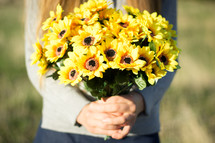 Girl holding bunch of yellow flowers