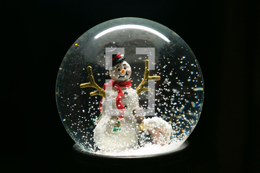 a snowman in a snow globe against a black background 
