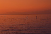 paddle boarders on a the water at sunset 