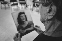elderly woman looking at an old photograph from her youth 