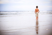 a boy standing on a beach 