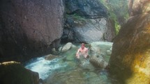 Young Man Cold Plunging Below A Waterfall