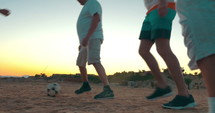 Low angle view of a group of people playing football (soccer) on a beach.