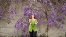 Woman joyously throwing wisteria petals in the air.