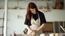 Girl potter forms her product on the board.