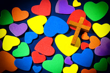 Wooden cross on colorful hearts.