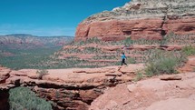 Sedona is known for its red sandstone formations and energy vortexes. Tourist walking on Devil's Bridge hike