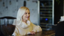 Smiling blonde girl makes order in coffee shop to bartender woman.