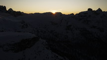 Sun rises over snowy mountain ridge, Dolomites Italy aerial sunrise view