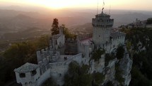 Aerial drone shot orbiting tower in a medium shot on side of cliff at sunset.
