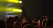 Female hands clapping her hands high in the air at a concert.