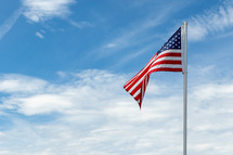 American flag on pole waving against blue sky