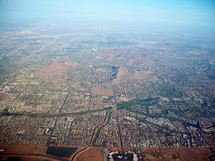 An aerial view from the sky over the earth of the city of Phoenix, Arizona from an airplane showing the outline of the city and buildings and the horizon over the earth.  