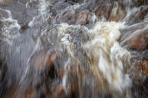 Water rushing over rocks along river rapids 