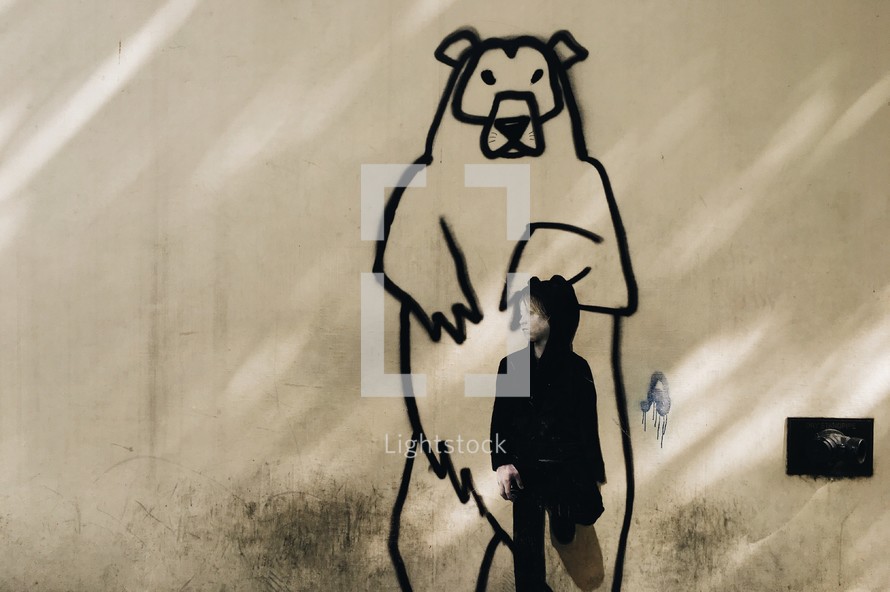 a child in front of a street art painting of a grizzly bear 