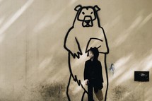 a child in front of a street art painting of a grizzly bear 