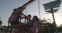 Children swinging together at a public playground.