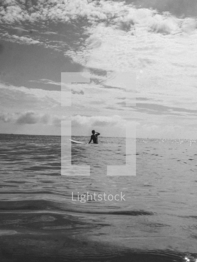 A black and white image of a surfer waiting for the next wave