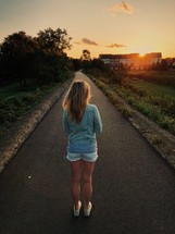 a young woman standing in the middle of a paved path 