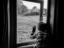 a toddler boy looking out a window 