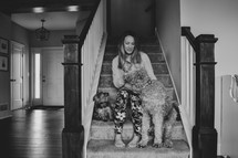 a woman sitting on steps with her dogs at home 