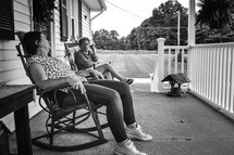 mother and adult daughter sitting in rocking chairs on a front porch 