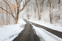 Winter scene of snowy road through the woods between trees