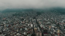 Aerial Panoramic View Of Crowded Cityscape Of Quito Against Misty Sky In Ecuador.	