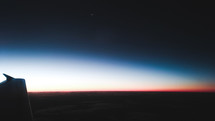 wing of a plane in flight at dawn 