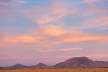 Colorful sunrise over distant mountains and dry field