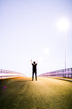 a man standing in the middle of a road with his hands raised 