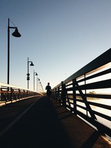 a woman jogging across a bridge 