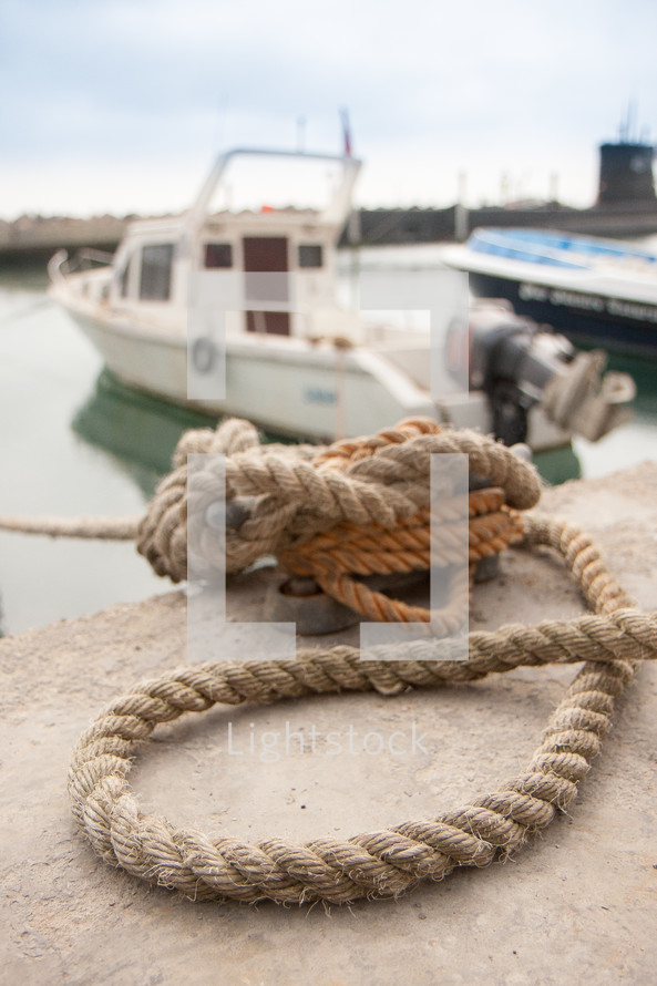 rope knotted to secure boat to dock at a harbor marina