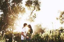couple hugging outdoors in a field under sunlight