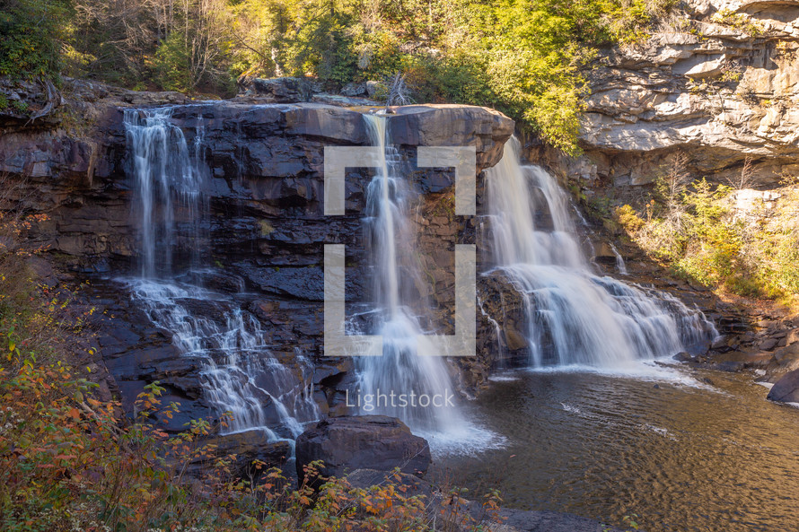 Silky waterfall in the woods flowing down rocks slow shutter speed