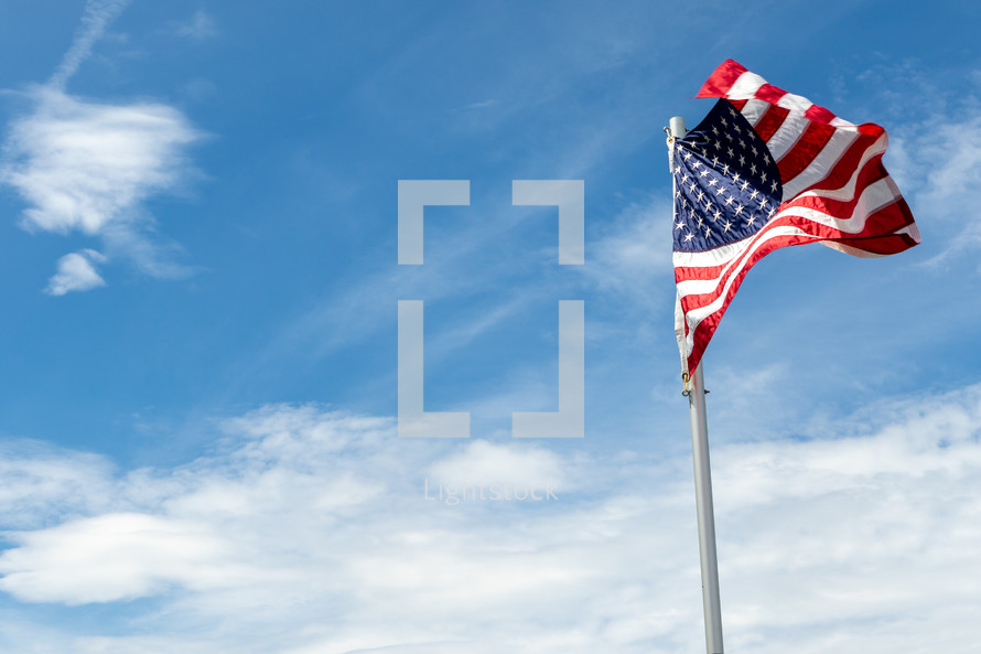 American flag on pole waving against blue sky 