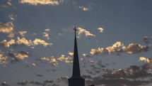 Time lapse of clouds beyond a church steeple at sunset