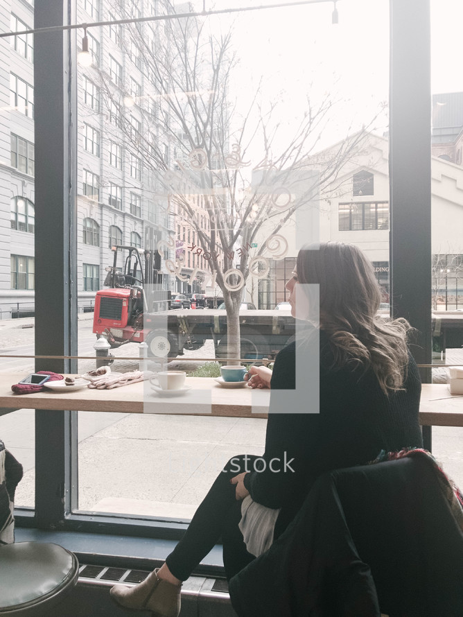 woman sitting in a window seat of a coffee shop 