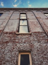 looking up at the side of a brick building with windows 