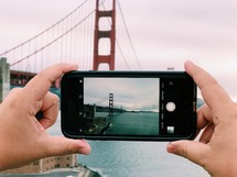 a person taking a picture of the Golden Gate bridge with their cellphone 