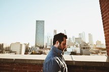 man on roof with city