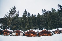 Multiple small wooden cabins in the snow in the trees in Switzerland